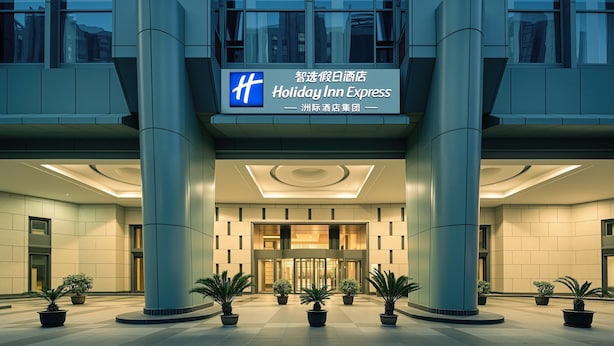 A modern hotel entrance with a Holiday Inn Express sign, large columns, and potted plants. - Holiday Inn Express Beijing Guomao CBD By IHG (Beijing)