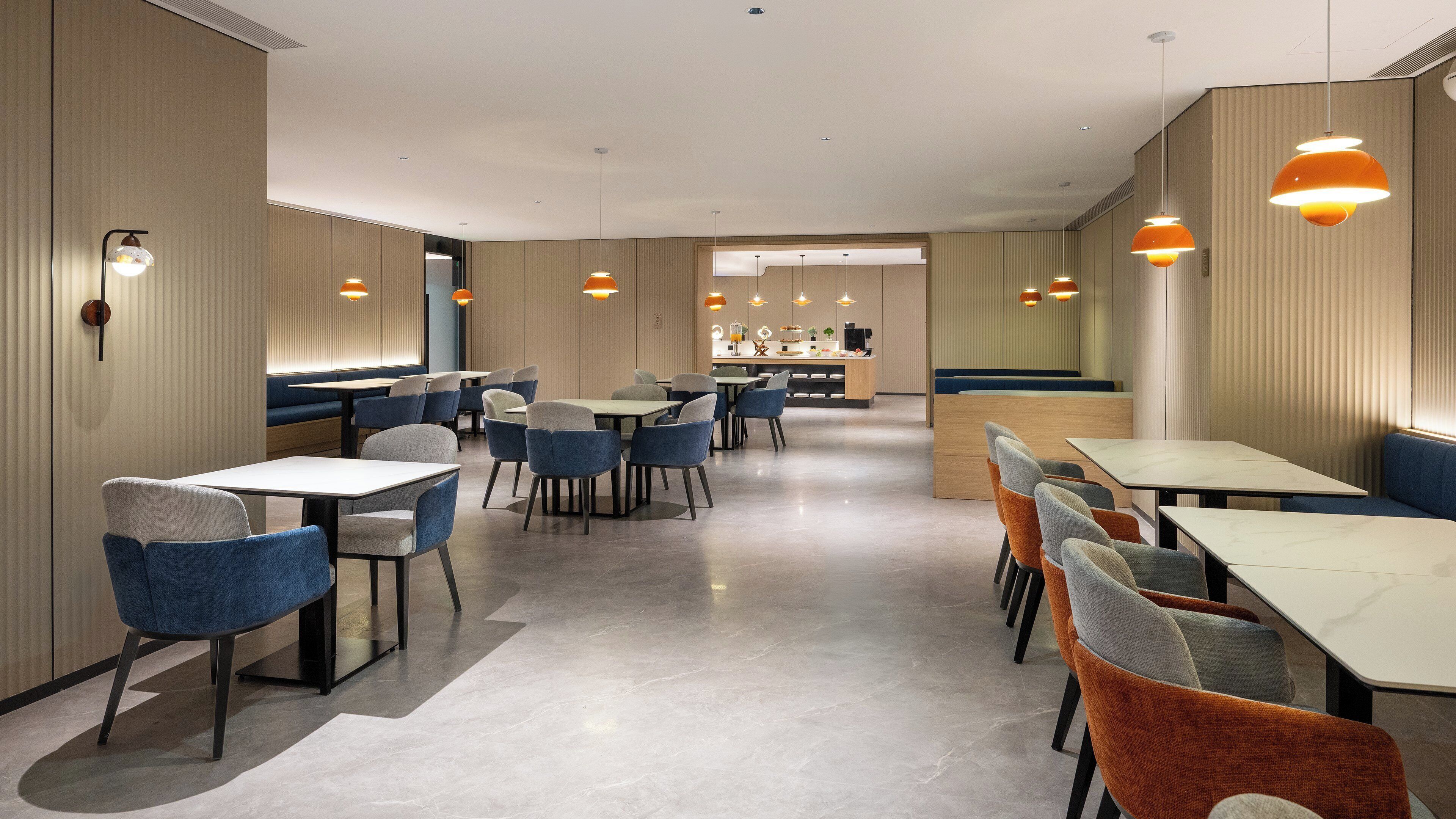 A modern restaurant interior with booths, tables, and pendant lighting.