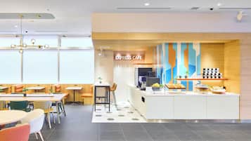 Un café moderno con mostrador central, zona de mesas y una pared decorativa.