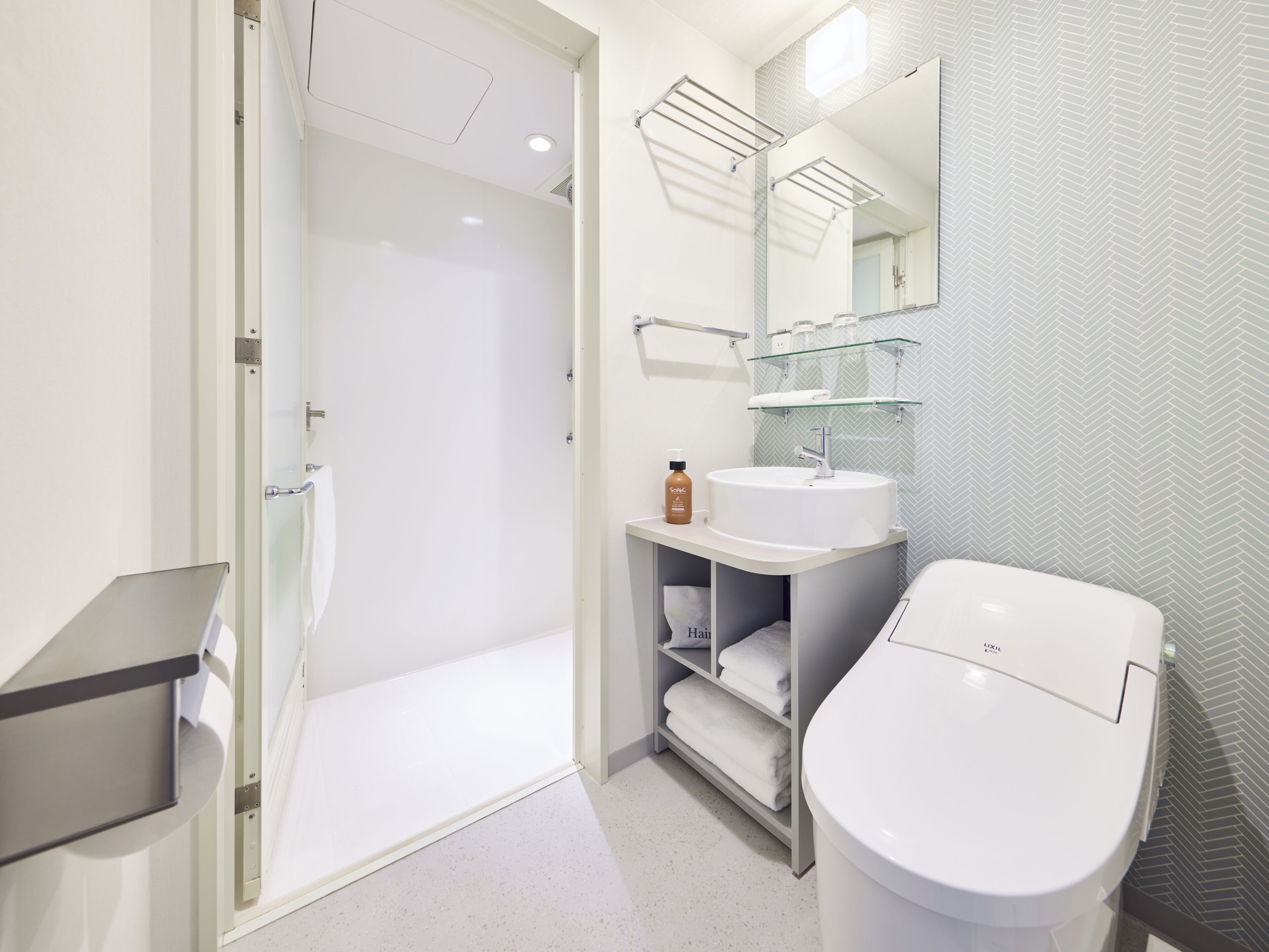 A modern bathroom with a glass shower enclosure, a white sink, and a toilet.