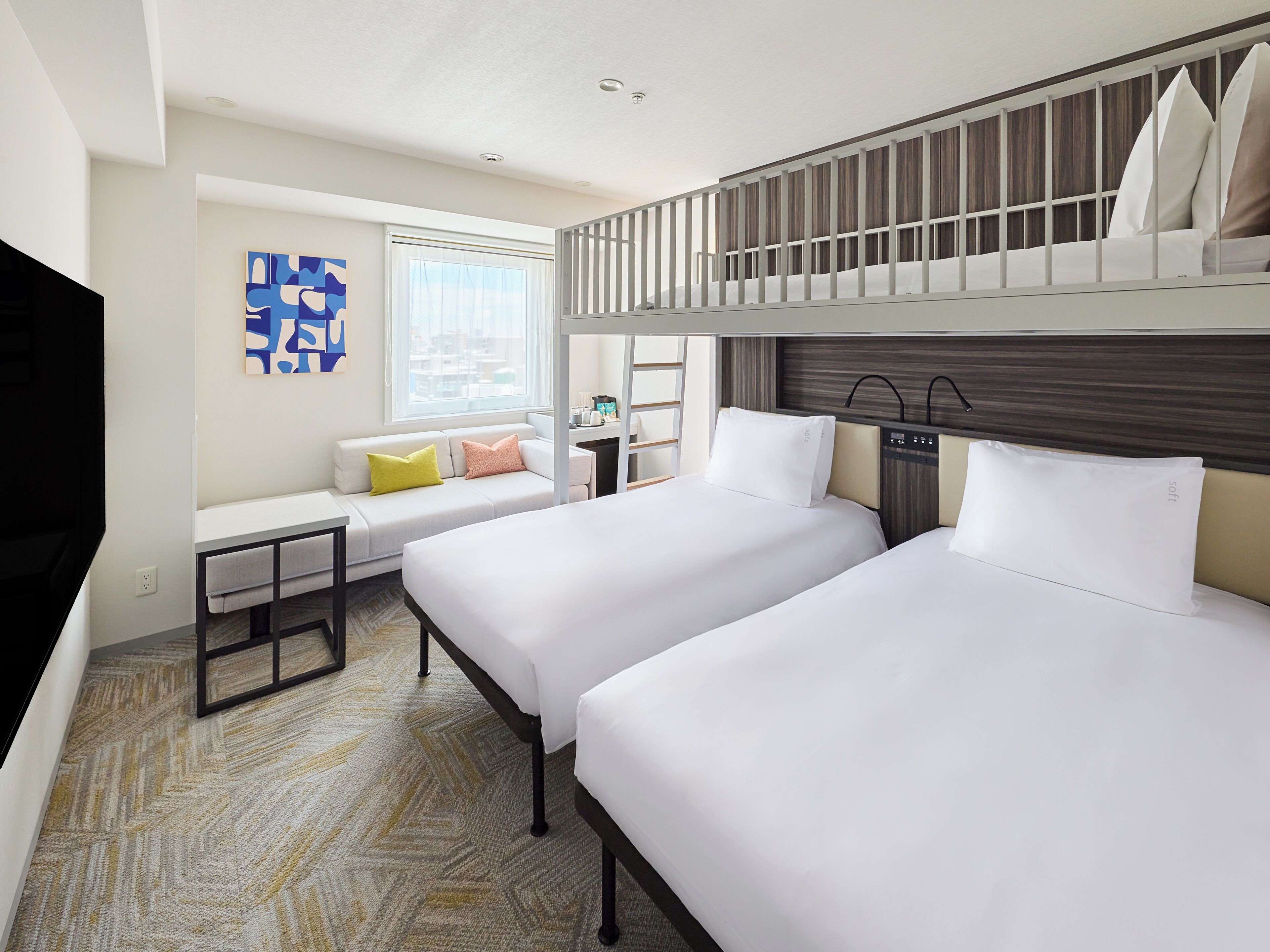 A hotel room with two beds, a sofa, a TV, and a window with a view.