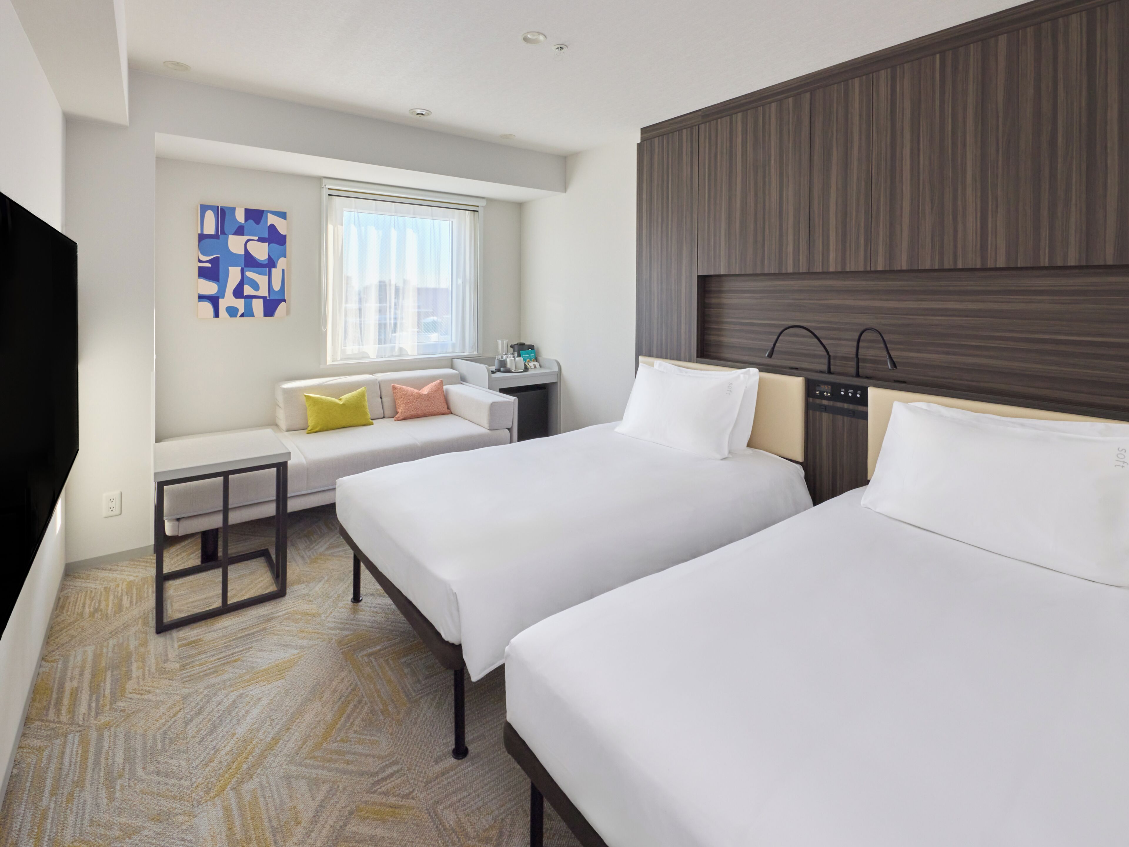 Una habitación de hotel con dos camas, un sofá, una mesita y un televisor.
