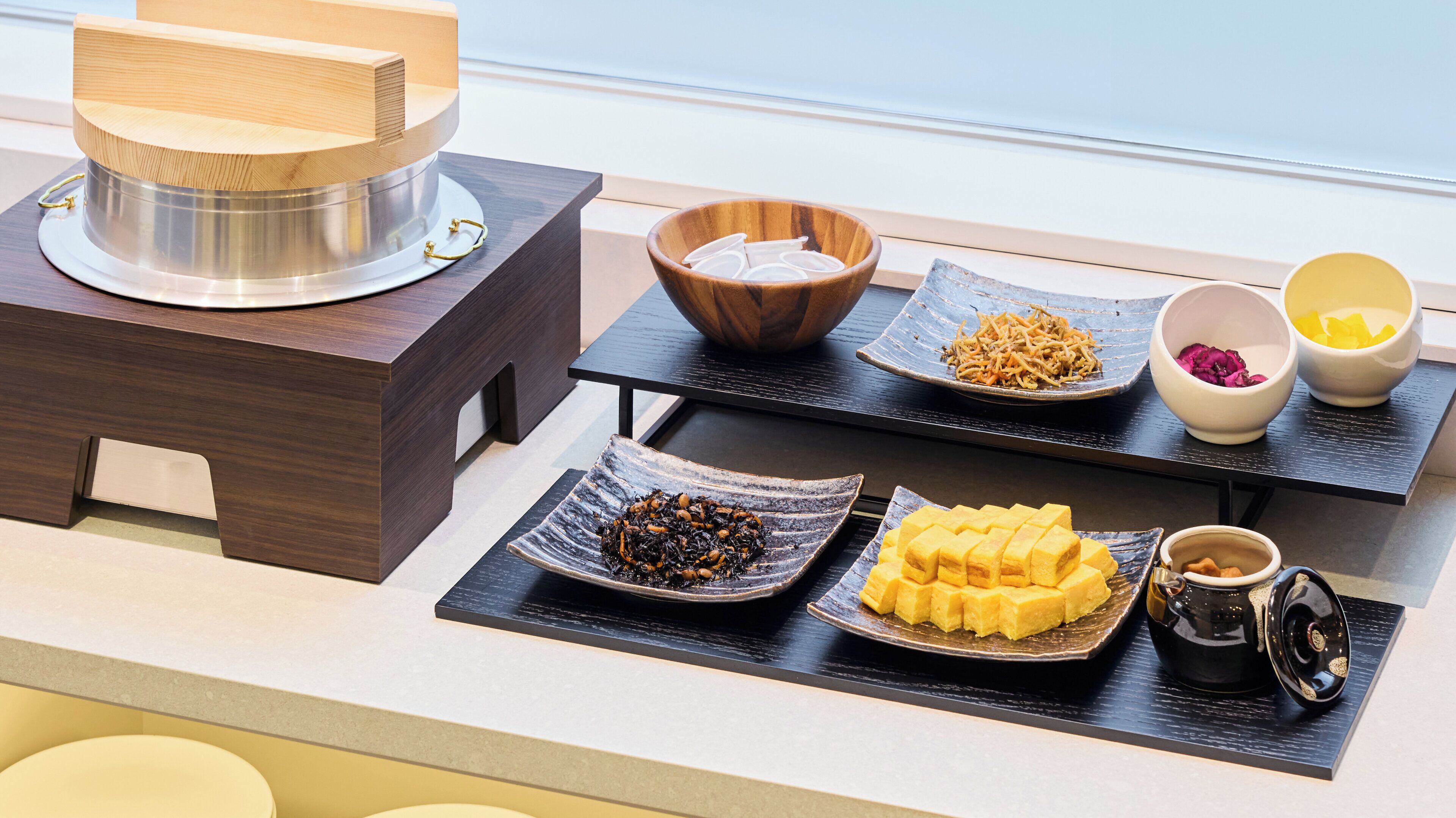 Un bufé de desayuno con diferentes platos y una cafetera sobre una mesa de madera.