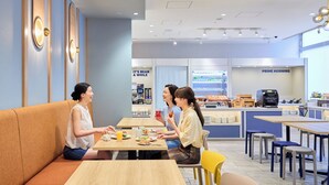 A café interior with seating arrangements, a coffee machine, and a breakfast counter. - Holiday Inn Express Sapporo Susukino by IHG (Sapporo)
