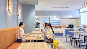 A café interior with seating arrangements, a coffee machine, and a breakfast counter.