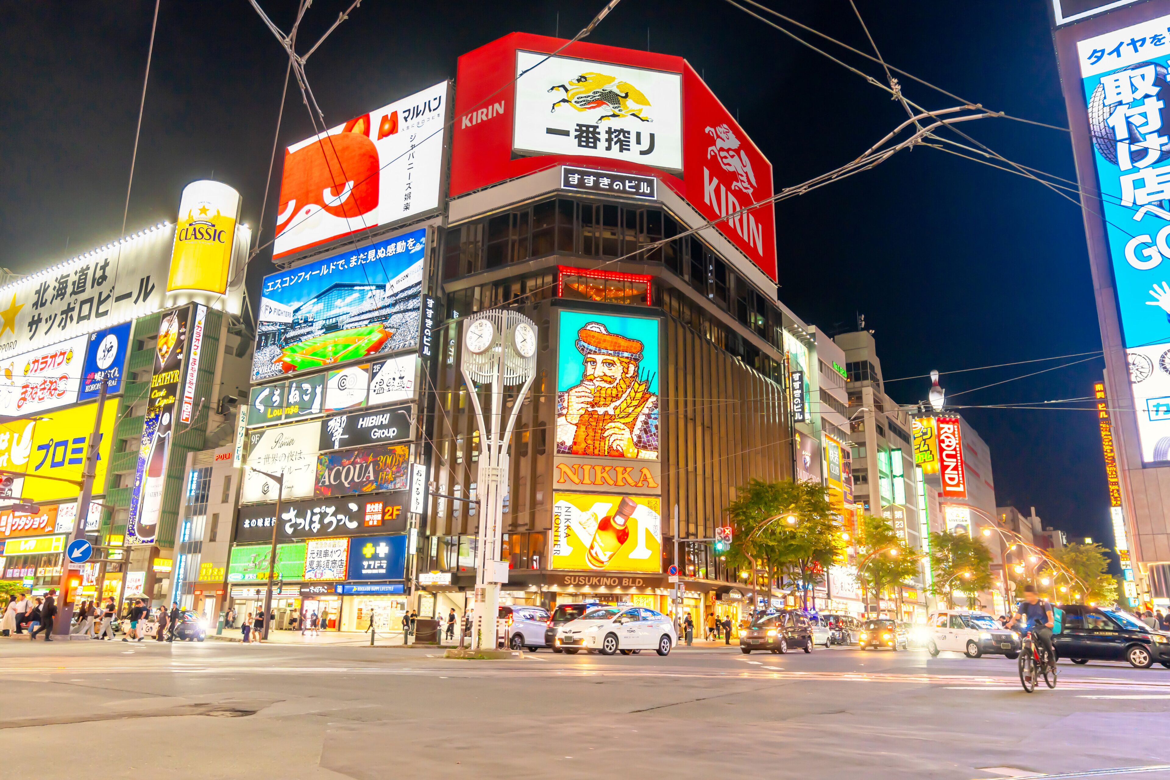 A busy urban street at night with illuminated billboards and signs.