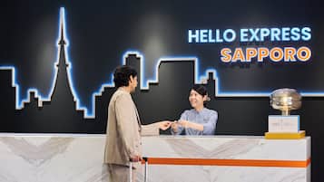 Un comptoir d’accueil avec une enseigne « Hello Express Sapporo », un trophée et un sol en marbre.
