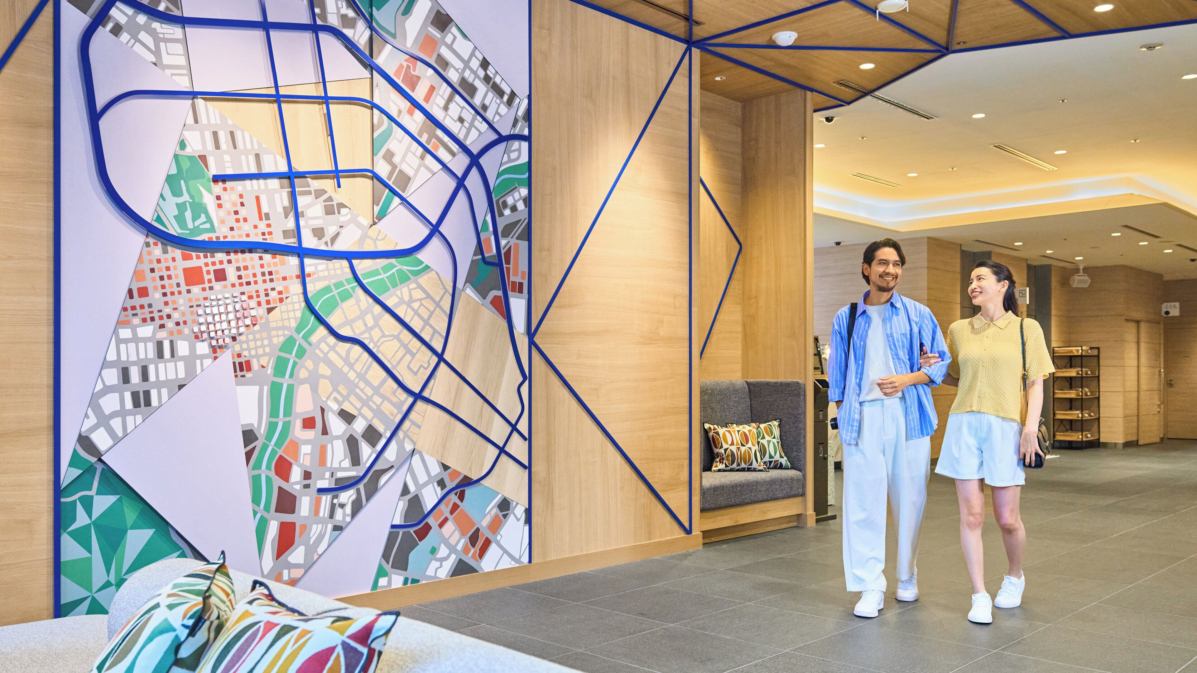 A modern hotel lobby with a large city map mural, a sofa, and a seating area.