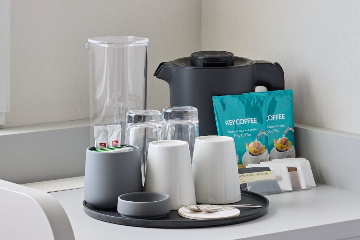 A coffee maker, coffee pods, a coffee grinder, a coffee bag, and a powdered creamer on a countertop.