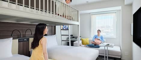 A hotel room with a bunk bed, a sofa, a small table, and a TV.