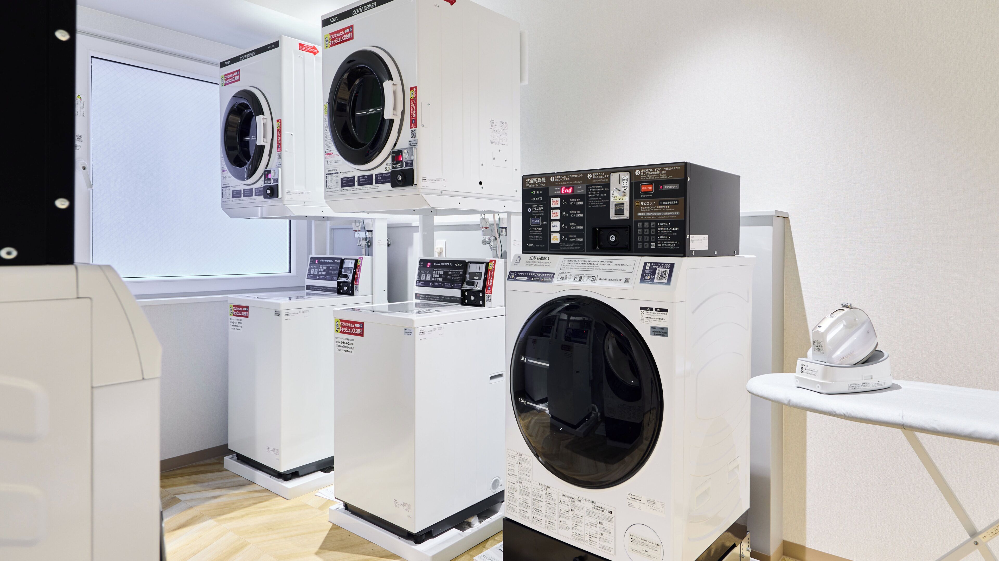 A laundry facility with multiple washing machines and dryers, including a front-loading washer and a top-loading dryer.