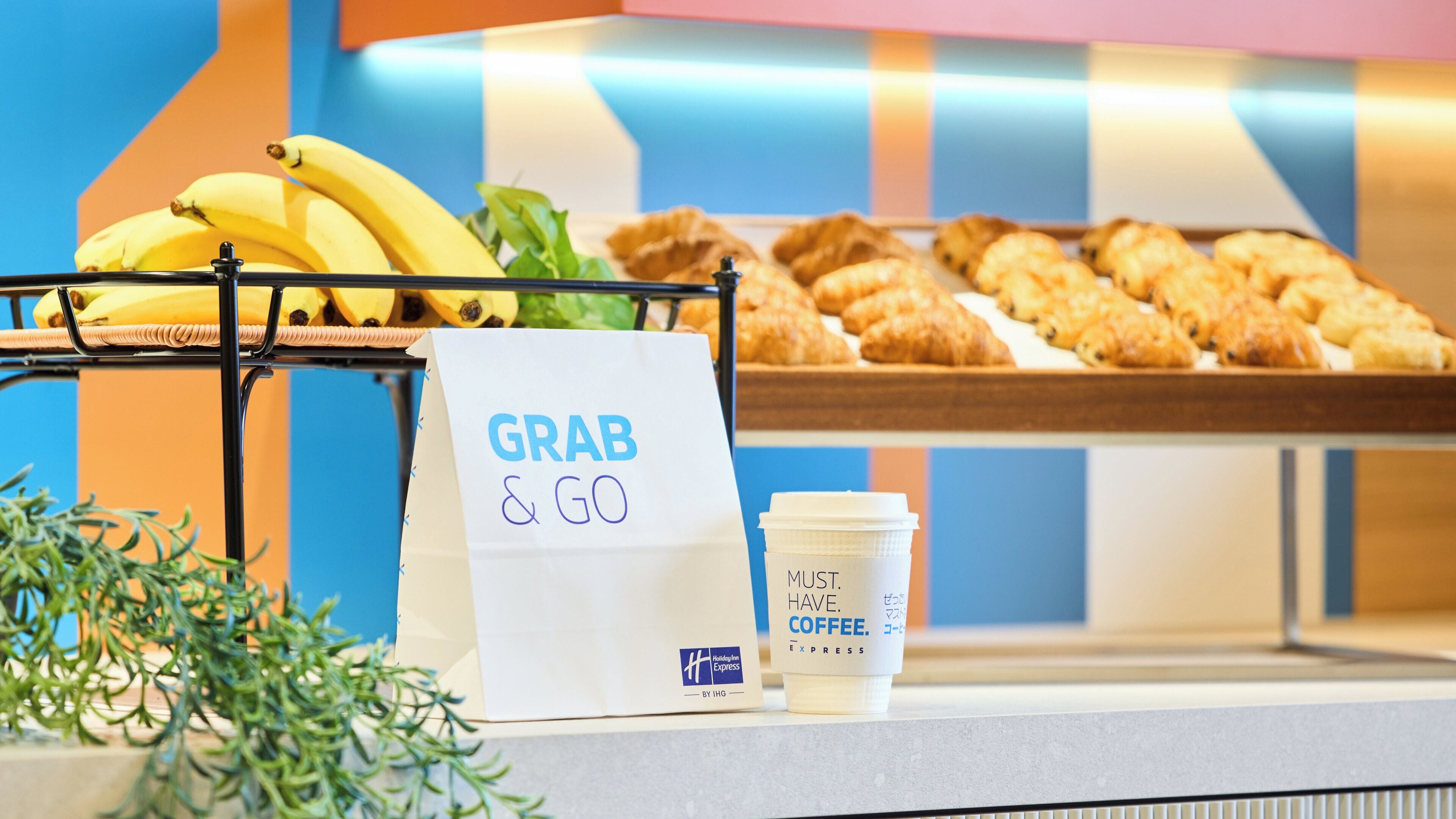 A buffet setup with a 'GRAB & GO' sign, a coffee cup, and a basket of bananas.