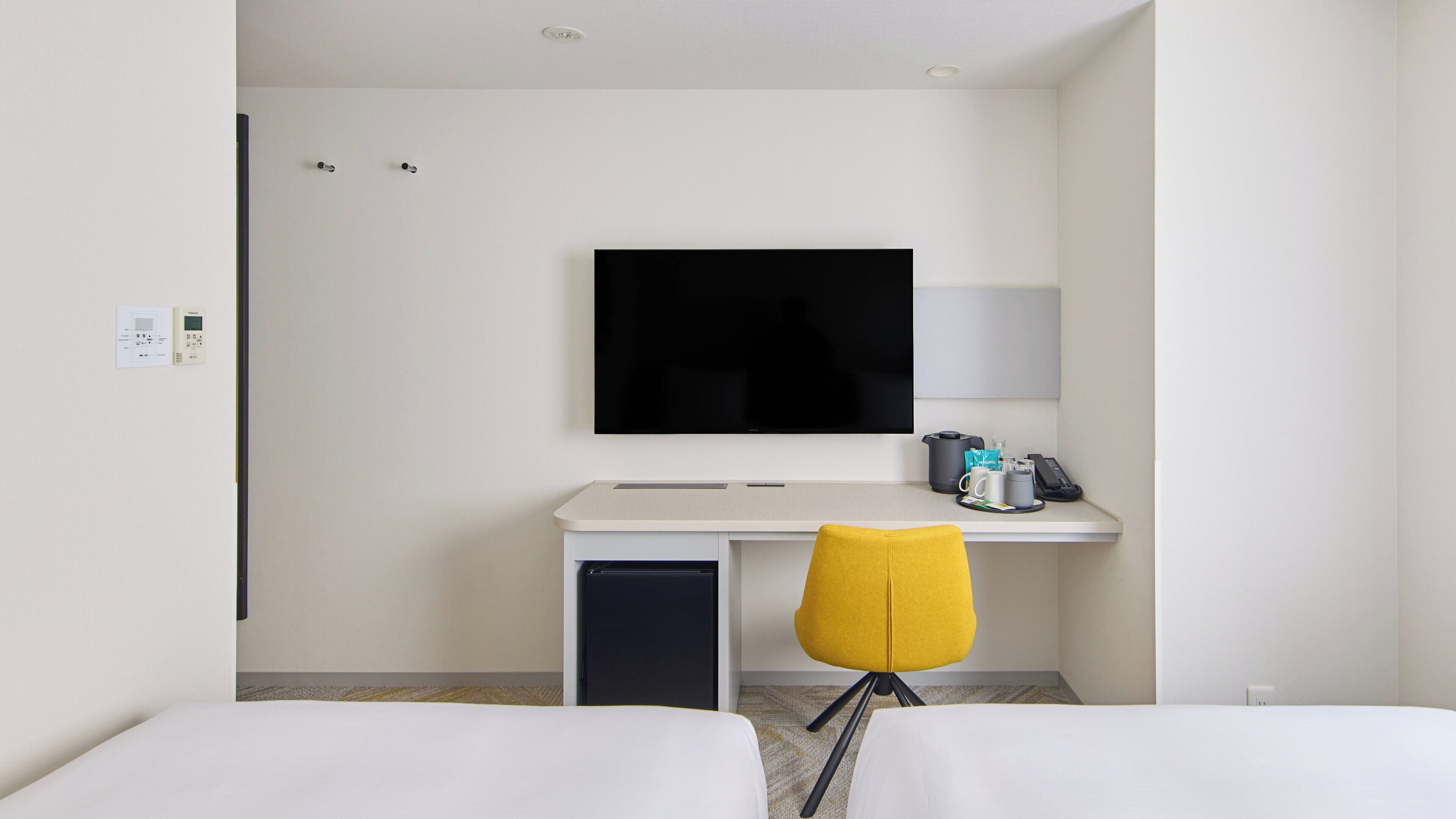 Une chambre d’hôtel comprenant un lit, un bureau avec un téléviseur à écran plat, une chaise et une machine à café.