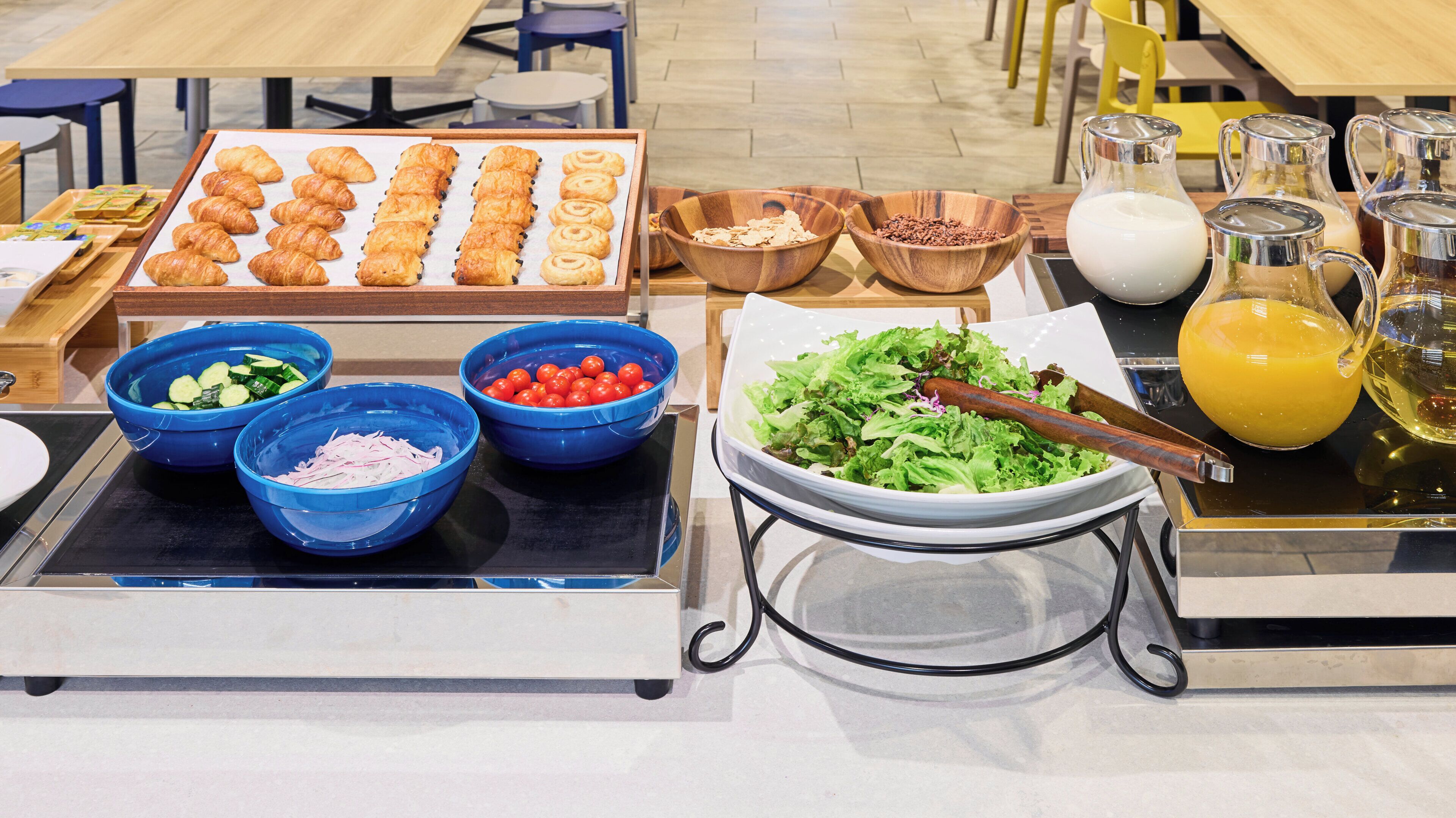 A buffet with various food items including croissants, salads, and beverages.