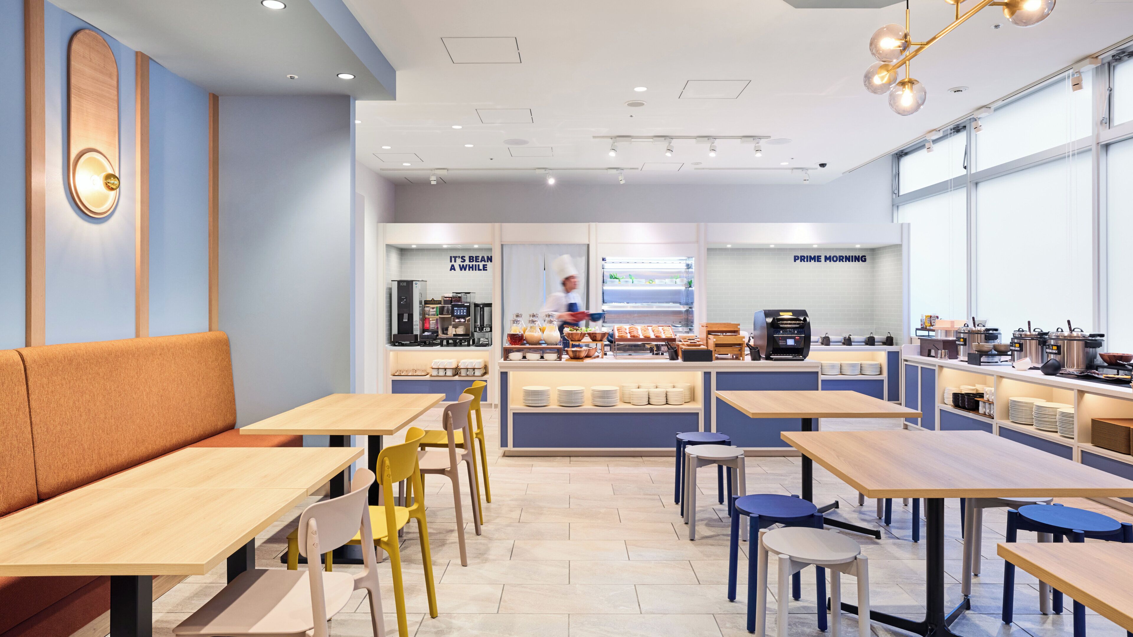 Un café avec des tables et des chaises, un comptoir où sont exposés des produits alimentaires et une machine à café.