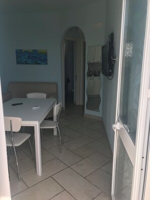 Una habitación con una mesa de comedor, sillas, un sofá, un televisor y un cuadro en la pared.
