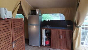 A compact kitchenette with a refrigerator, microwave, and gas stove.