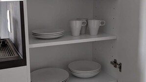 A white interior with shelves holding plates and cups. - Gauaz Boardinghouse  (Maisach)