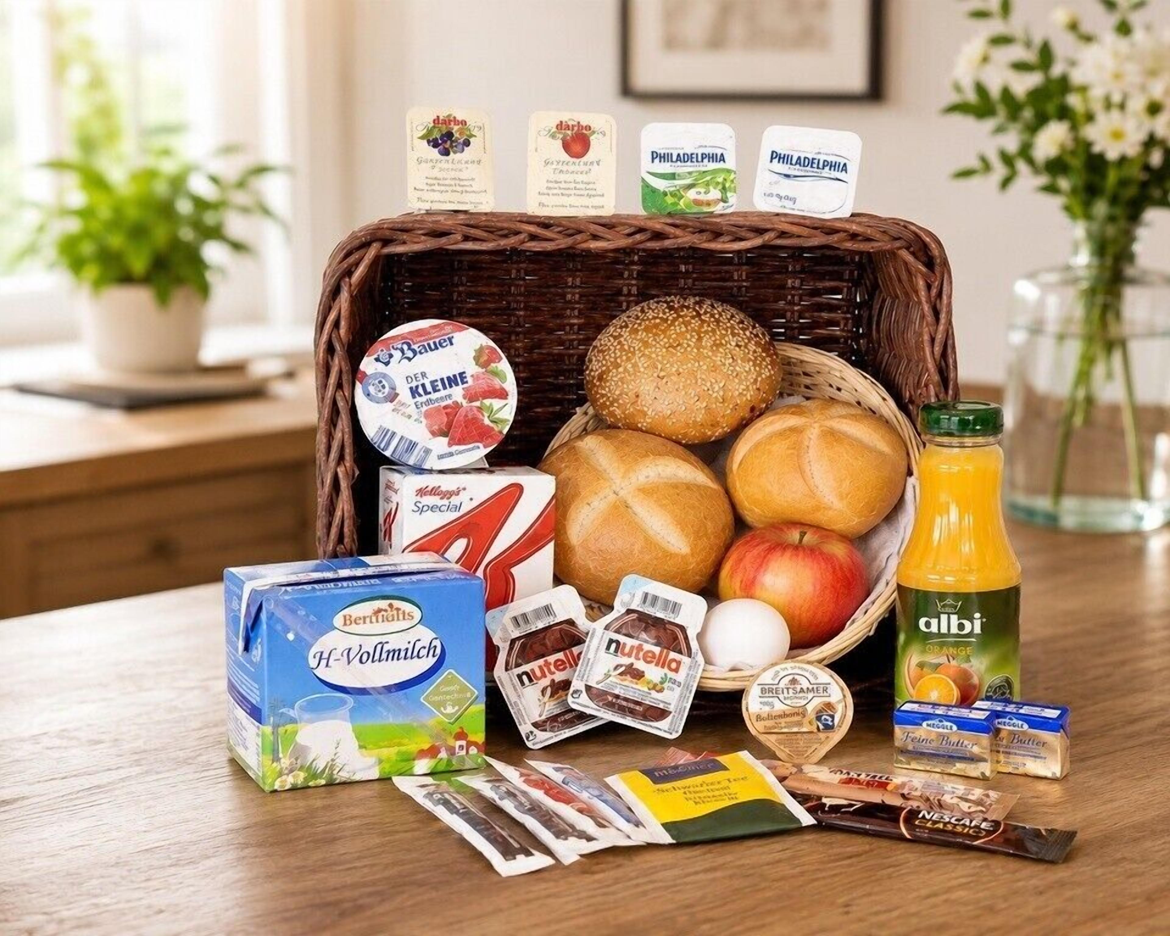 Una cesta de desayuno con pan, huevos y jugo, junto con diversos bocadillos envasados y productos lácteos.