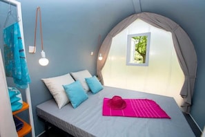 Ein Schlafzimmer mit Bett, Kissen, einem Hut, einem Regal und einem Fenster mit Blick.