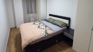 Une chambre à coucher avec un lit, une table de chevet, une armoire et une fenêtre avec des rideaux.