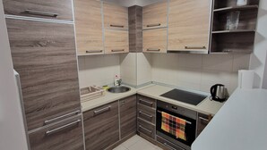 Une cuisine moderne avec des meubles en bois, un évier, une cuisinière et une poubelle.