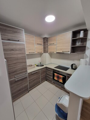Eine moderne Küche mit Holzschränken, einer Spüle, einem Herd und einem Mülleimer.
