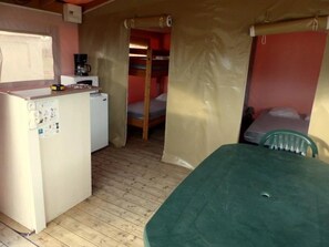 Habitación pequeña con kitchenette, cama individual y una mesa.