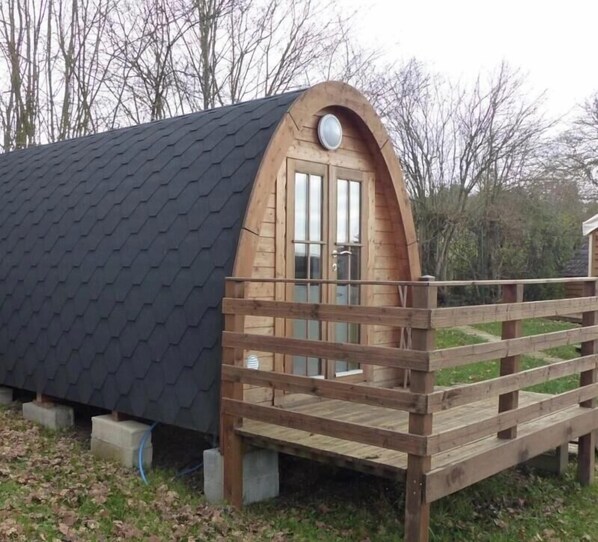 A wooden cabin with a sloped roof, a wooden deck, and a single door.