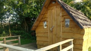A wooden cabin with a porch, a door, and a window.
