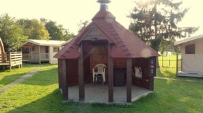 A small wooden structure with a sloped roof, a door, and a bench.