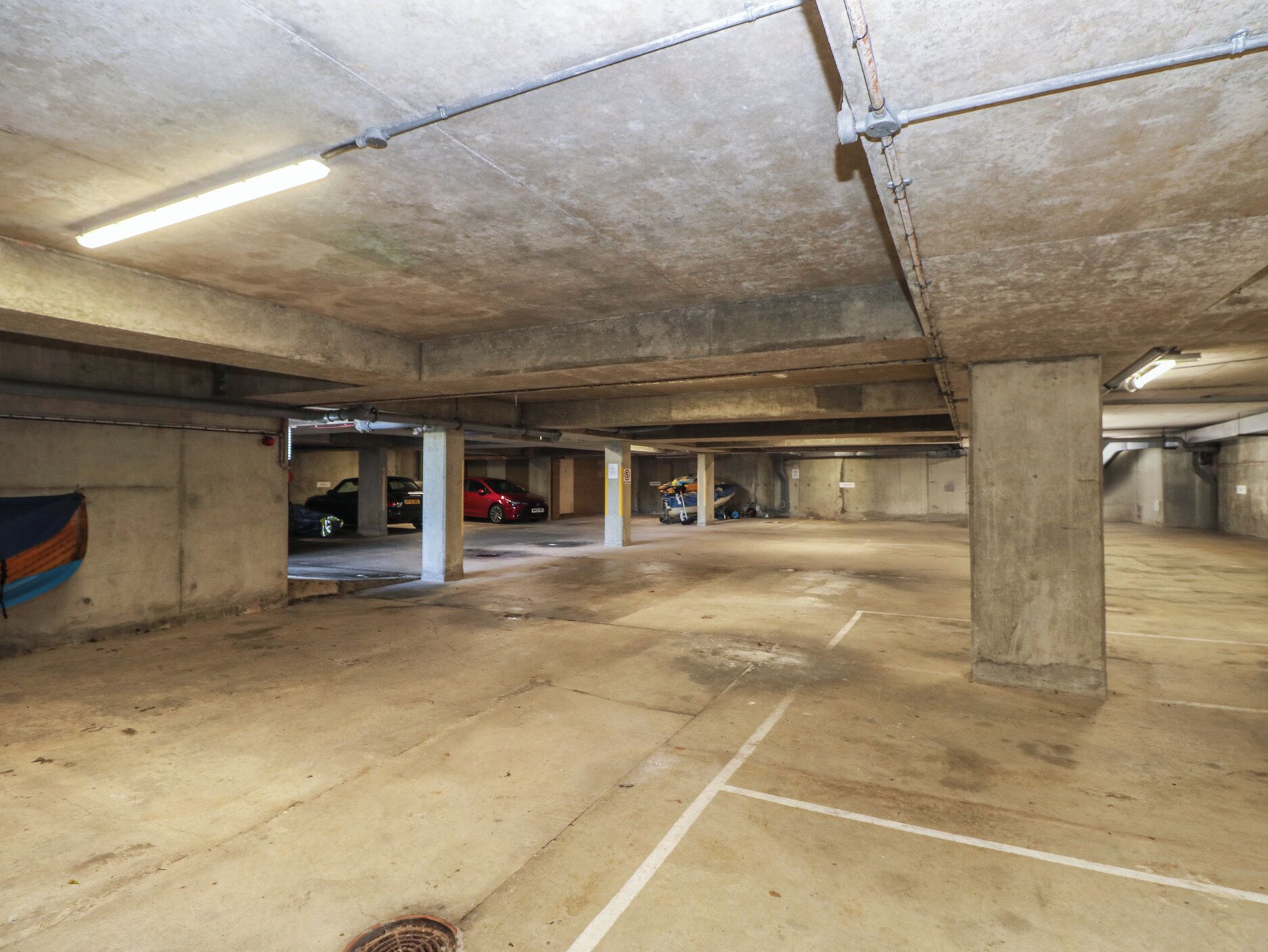 A multi-level parking garage with concrete pillars, marked parking spaces, and overhead lighting.