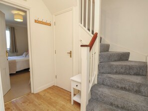 A staircase with a wooden handrail leading to a bedroom with a bed and a nightstand. - Anchorage House (Seaview)