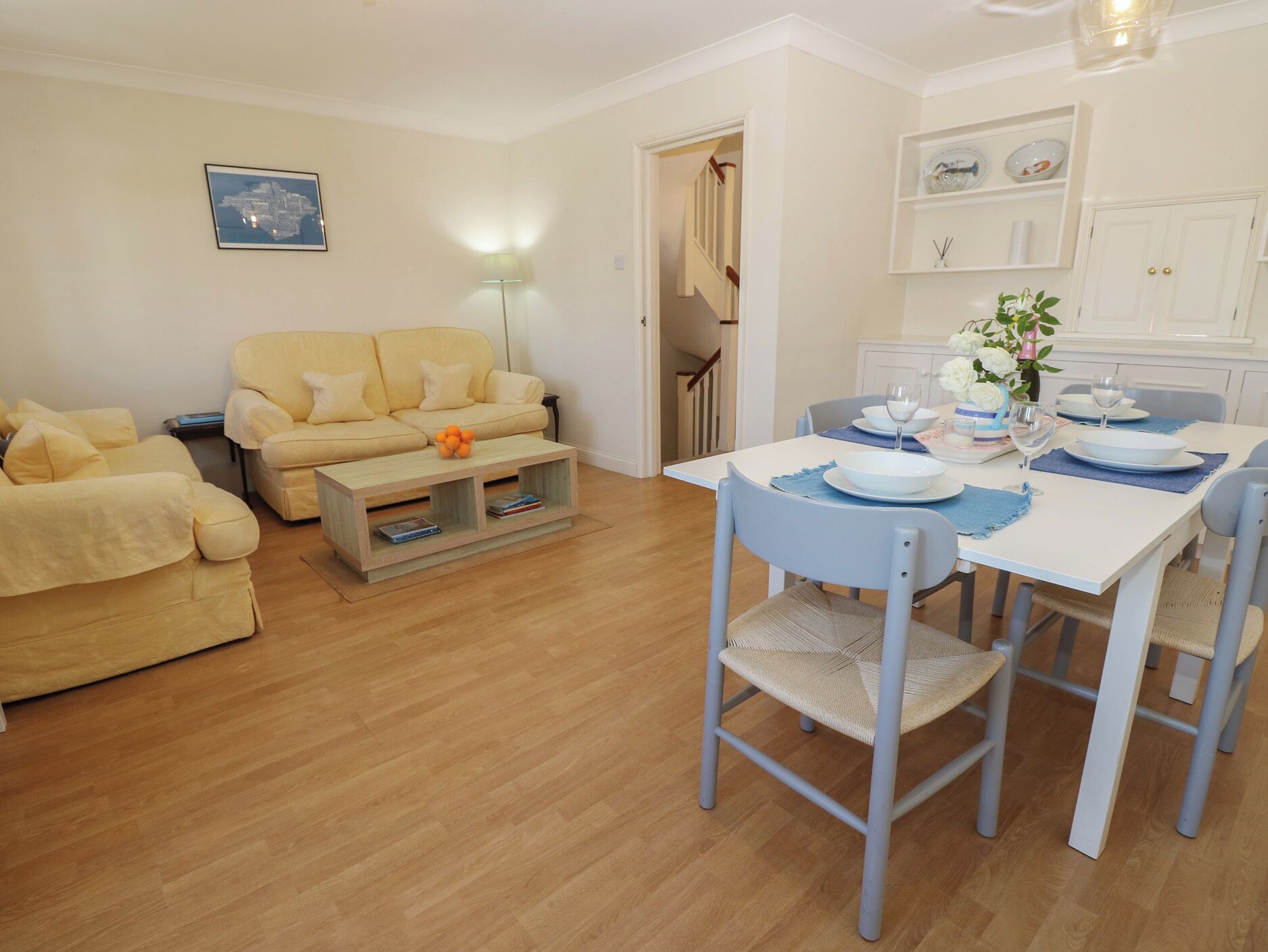 A living room with a sofa, a coffee table, and a dining area with a table set for two.