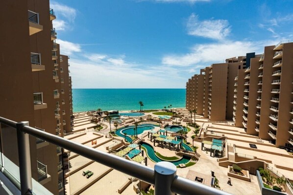 Ein Resort mit mehreren Schwimmbecken, einem Strand und Hochhäusern.