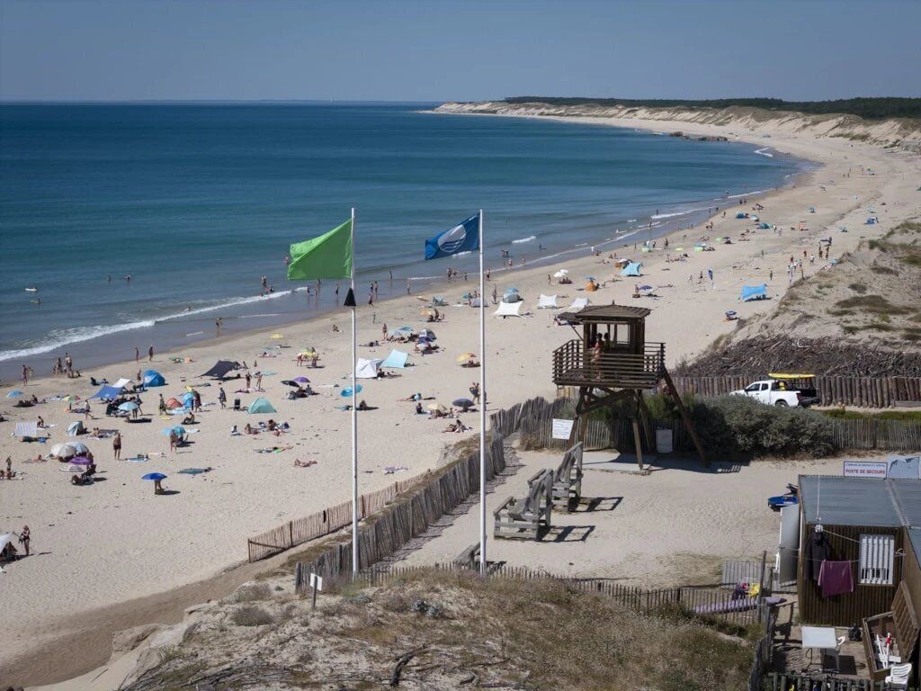 Una playa con tiendas de campaña, una torre de salvavidas y una valla de madera.