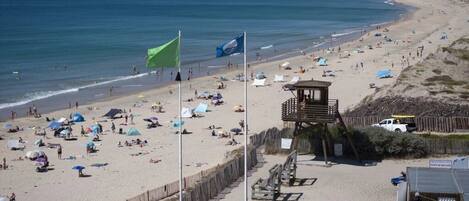 A beach with tents, a lifeguard tower, and a wooden fence.