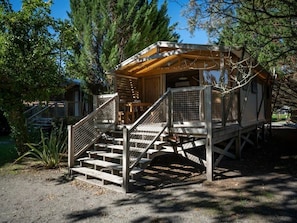 Une cabane en bois avec un escalier menant à une terrasse, entourée d’arbres.
