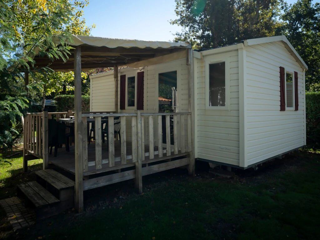 A small, single-story mobile home with a porch and a small deck.