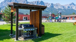 A barbecue grill, a playground, and a mountain view. - Canmore Studio w/ Kitchen | Sauna & Mountain Views (Canmore)