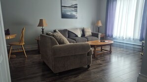 Una sala de estar con un sofá, dos lámparas, una mesa de centro y un cuadro en la pared.