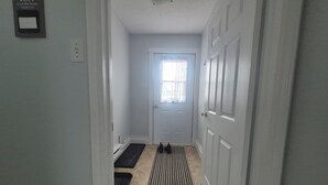 Un pasillo con una puerta, felpudo, alfombra y un cartel con la contraseña de WiFi.
