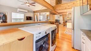 A laundry area with two washing machines and a dryer, wooden beams on the ceiling, and a refrigerator. - Rustic Vibrant Loft in Montrose Houston (Houston)
