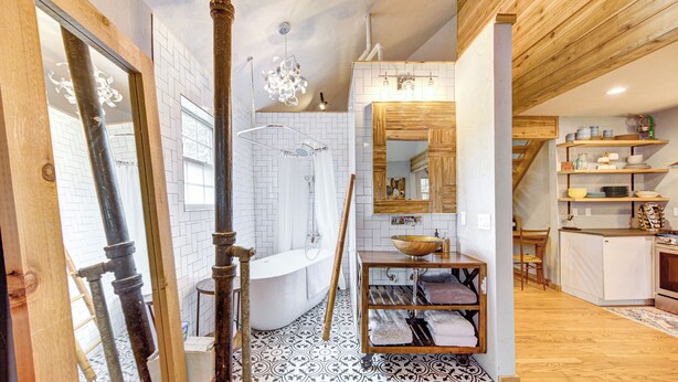 A bathroom with a bathtub, shower, and a wooden vanity with a bowl sink. - Rustic Vibrant Loft in Montrose Houston (Houston)