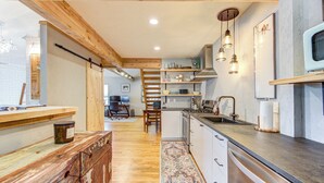 A kitchen with wooden beams, a central island, and a view into the living area. - Rustic Vibrant Loft in Montrose Houston (Houston)