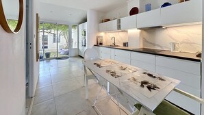 Una cocina moderna con armarios blancos, encimera de mármol y una mesa de comedor con una silla blanca.
