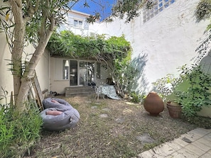 Ein Innenhof mit einem weißen Gebäude, einem Baum, einem Sitzsack und einem Blumentopf.