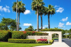 A landscaped entrance with palm trees, a sign reading 'The Palms,' and a well-maintained lawn. - NEW Palms at Wailea 2 Bedroom Garden-View Villa | Car Incl. w/ 6 nights | PAW-1706 by KBM (Lahaina)