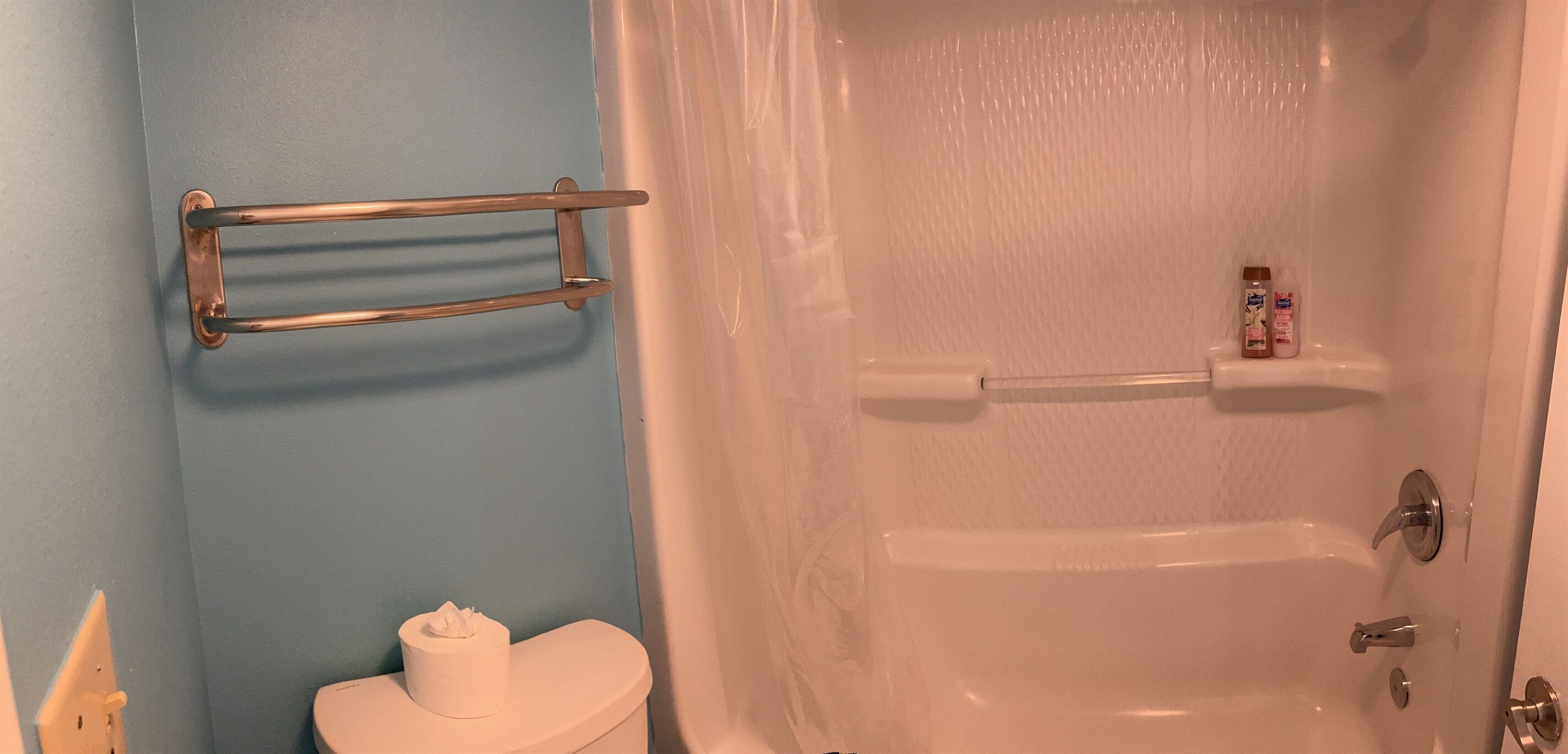 A bathroom with a toilet, a towel rack, and a bathtub.