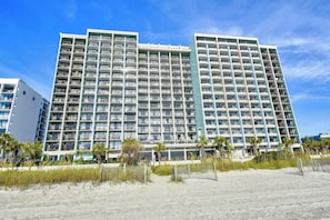 A multi-story hotel with numerous balconies, located near a sandy beach with palm trees. - 2BR Oceanfront Full Kitchen free Waterprk sleeps 7 (Myrtle Beach)